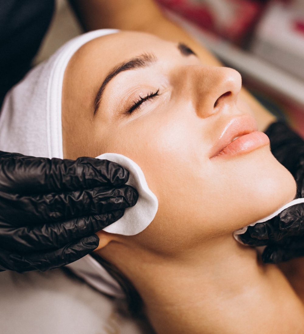 Cosmetologist cleaning face of a woman in a beauty salon