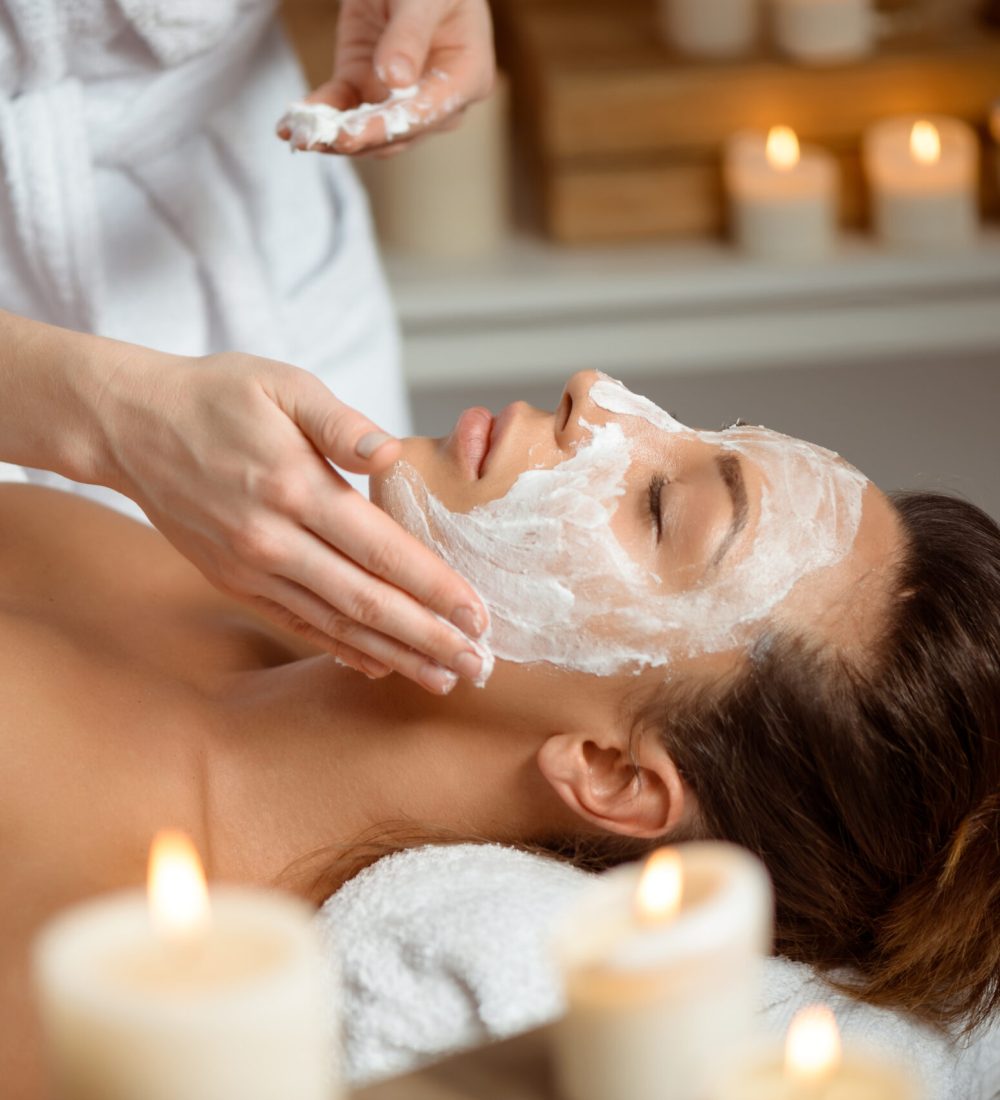 Young beautiful brunette girl in mask for face relaxing in spa salon. Eyes closed. Copy space.